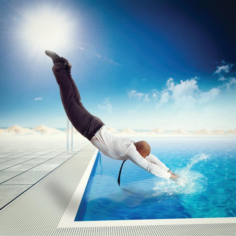A corporately dressed man diving into the pool