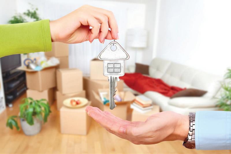 A hand giving a house key to another in a sitting room