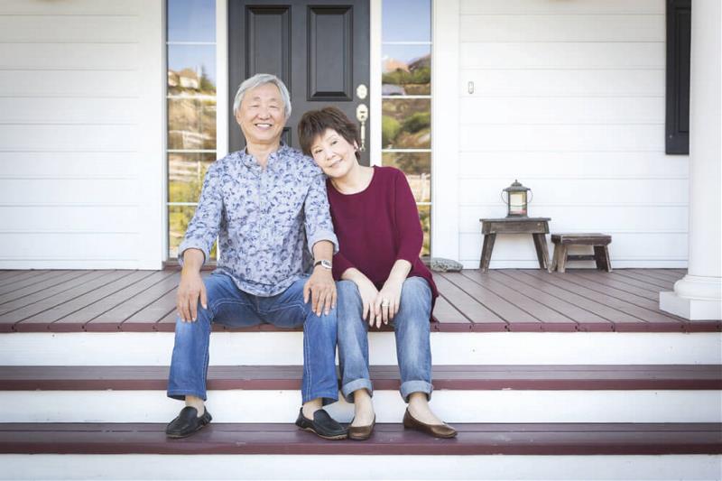 A couple sitting infront of their home