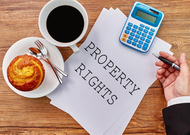 Property rights written on a sheet of paper, cup of coffee, calculator and cup cake