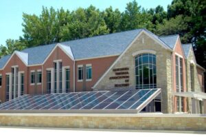 A modern building labeled "Wisconsin Association of Realtors" features large windows, pyramid-shaped glass structure, brick exterior, surrounded by trees.