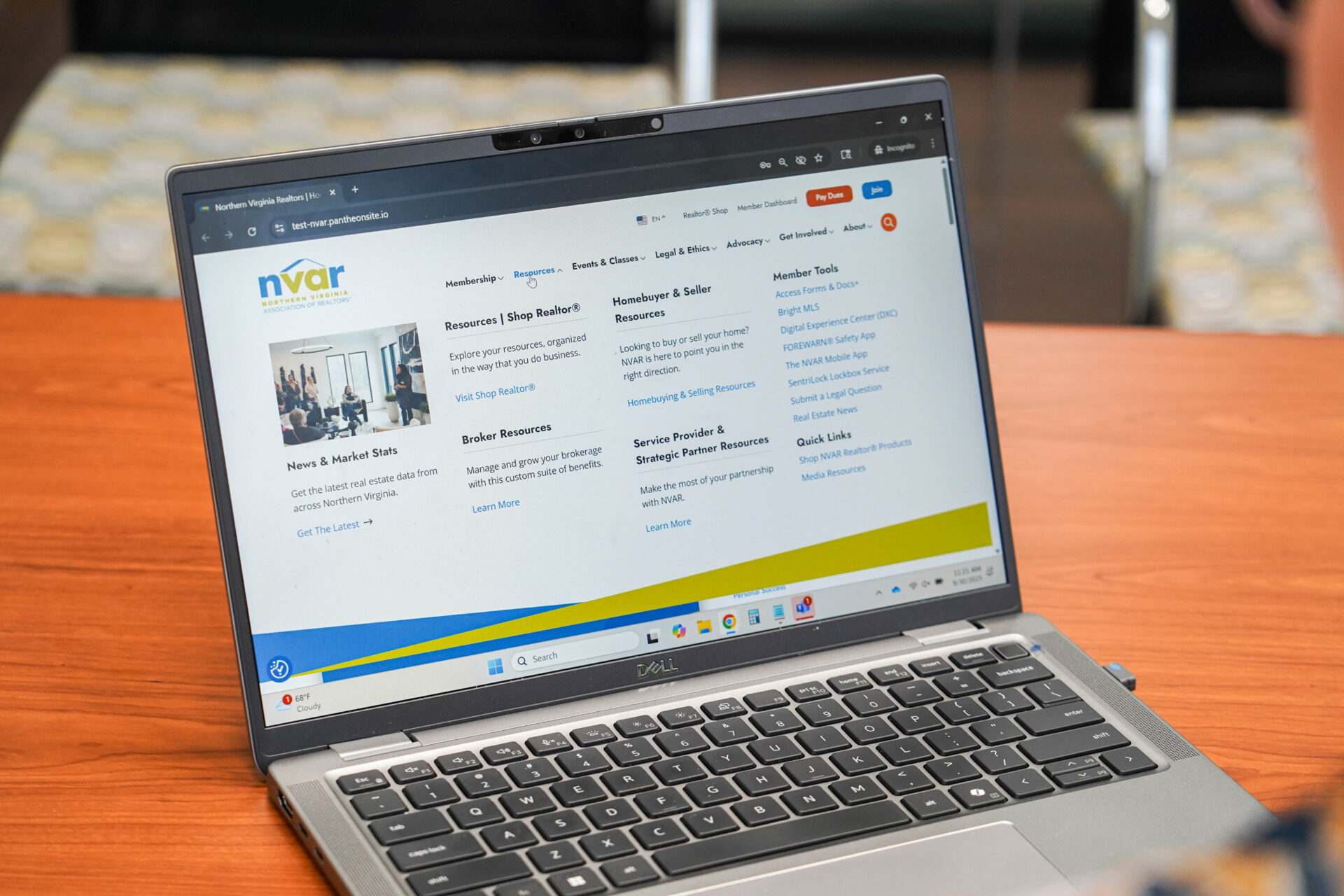 Navigating the New NVAR Website! A person using a laptop displaying a website page with resources and information. The scene is set on a wooden table indoors.