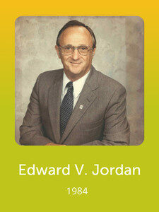 A person in a suit and tie stands against a neutral background. The text below reads "Edward V. Jordan, 1984" on a yellow-green gradient.