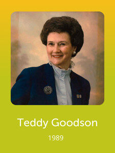 A person in formal attire smiles against a neutral backdrop. The text below reads "Teddy Goodson, 1989" on a green-yellow background.