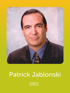 A person in a suit is shown in a formal portrait. The background is a soft gradient. Text below reads "Patrick Jablonski, 2002."