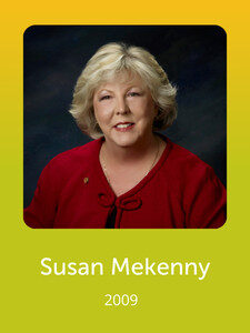 A portrait of a person with short, light hair wearing a red top. The text below reads "Susan Mekenney 2009" on a yellow background.