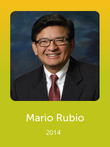 A person wearing glasses and a suit smiles against a studio background. The text below reads "Mario Rubio 2014" on a green background.