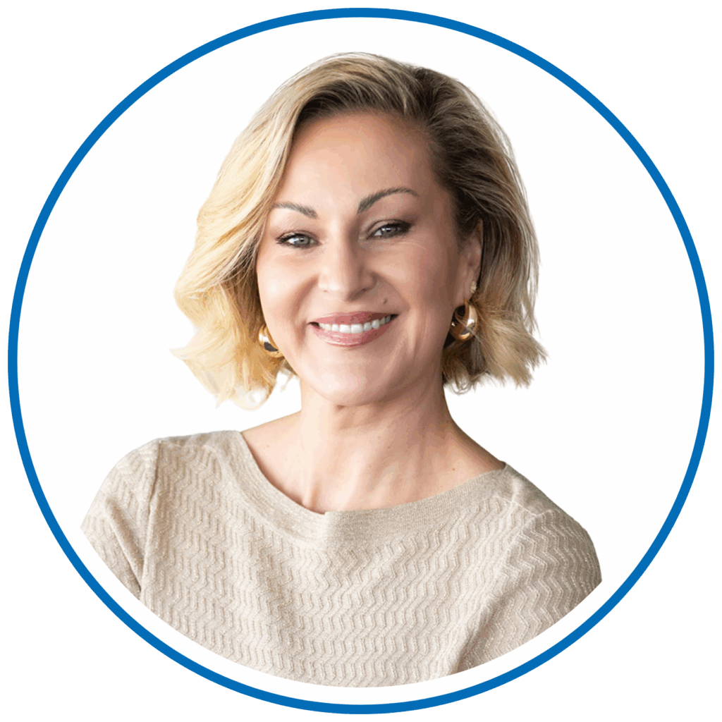 A person with short, wavy blonde hair, wearing a textured beige top, smiles against a plain white background within a circular frame.