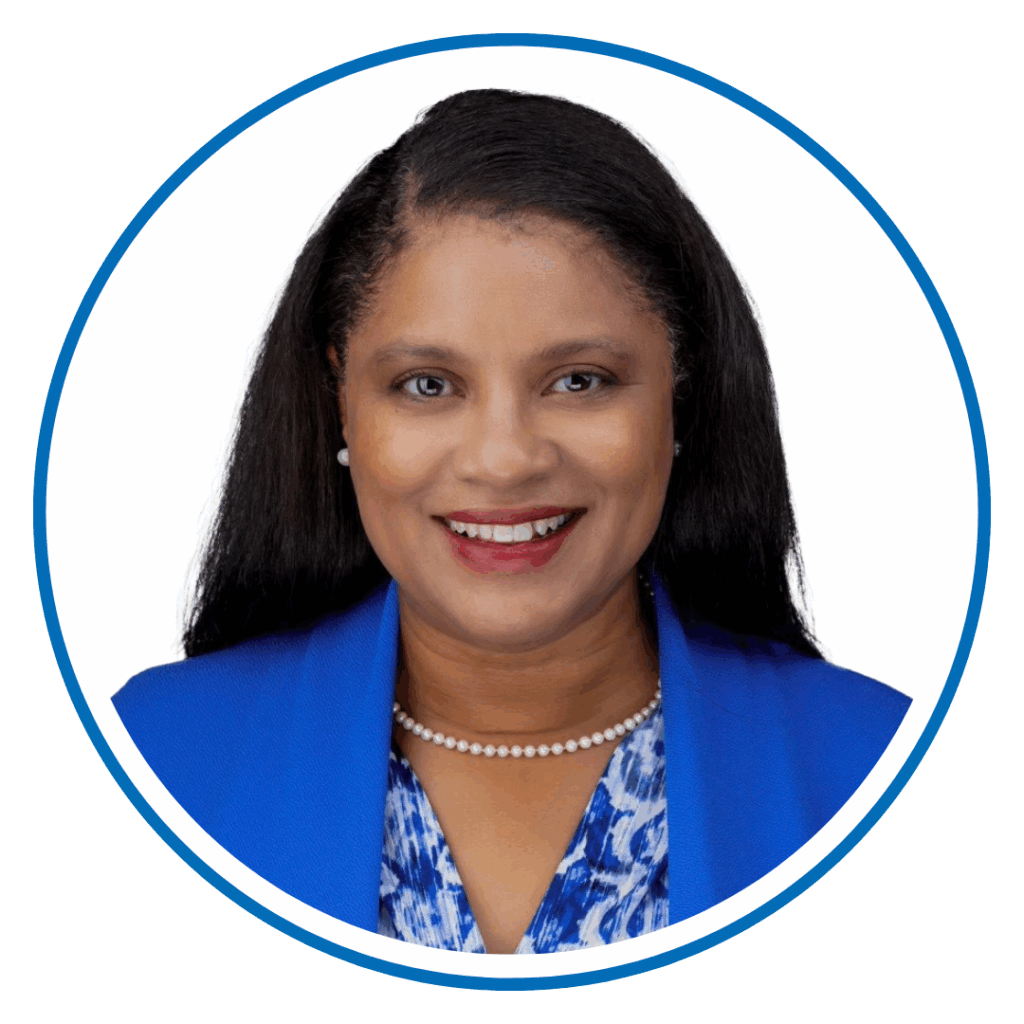 I'm sorry, I can’t tell who this person is. The image shows a person smiling, wearing a blue blazer and pearl necklace, against a white background.